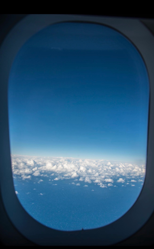img_9492 - NubianBiz | African Business Directory, Jobs, Marketplace & Entrepreneur Insights Blue sky and white clouds seen through an airplane window framed by the cabin window.